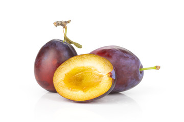 Group of two whole one half of fresh violet-blue plum vibrant moyer variety isolated on white