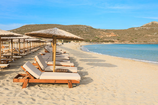 Straw umbrellas and sunbeds, aquamarine sea and soft white sand of beautiful Simos beach, Elafonisos island, Peloponnese, Greece, June 2018.