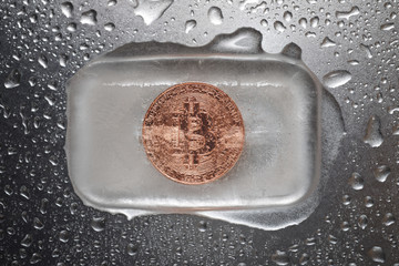 Overhead view of bitcoin in ice on wet metallic table