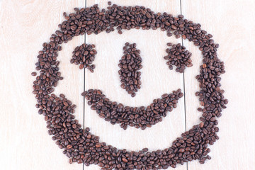 funny face of black coffee beans on wooden background