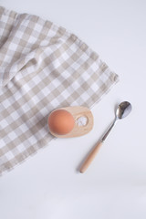 Served table for breakfast boild egg in wooden egg cup with salt spoon and checkered napkin White background Top view Minimalism Copy space