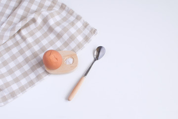 Served table for breakfast boild egg in wooden egg cup with salt spoon and checkered napkin White background Top view Minimalism Copy space