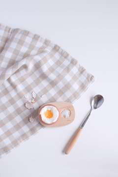 Served table for breakfast boild egg in wooden egg cup with salt spoon and checkered napkin White background Top view Minimalism Copy space