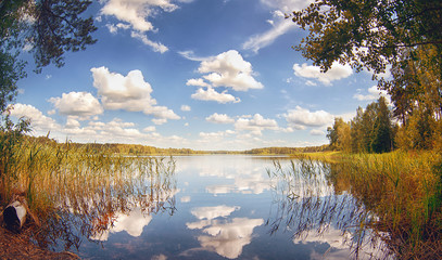 Lake in the forest on a summer day with clouds reflected in the water. Summer landscape.