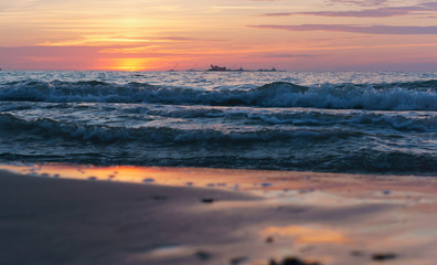 Obraz premium Sunset over the sea. Reflection of sunlight in the sea waves. Red sky in the rays of the sunset.