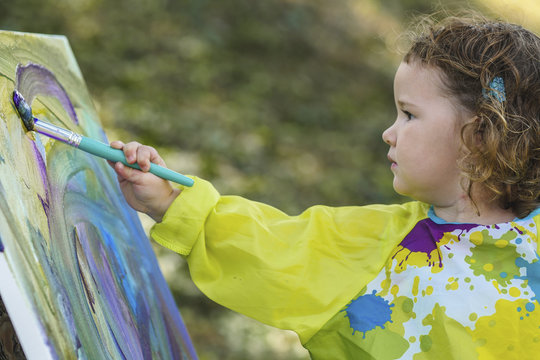 Side view of girl painting while standing outdoors