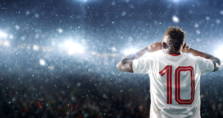 Soccer player celebrates a victory on the professional stadium while it’s snowing.