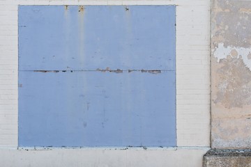 Whitwashed old brick wall with blue borded up window