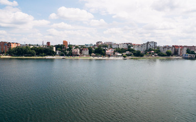 Naklejka premium Aerial View of beautiful green city, the embankment and the blue lake against the blue sky and white clouds. Ternopil. Ukraine