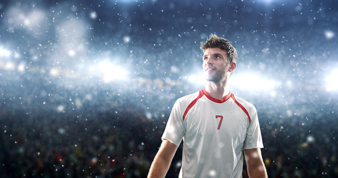Soccer player celebrates a victory on the professional stadium while it’s snowing.