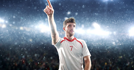 Fototapeta na wymiar Soccer player celebrates a victory on the professional stadium while it’s snowing.