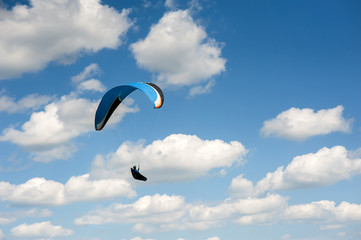 Paraglider flying in the blue sky against the background of clouds. Paragliding in the sky on a...