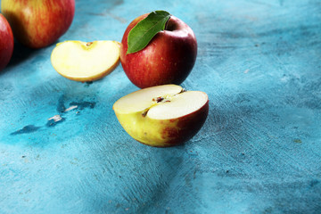 Ripe red apples with leaves on wooden background.