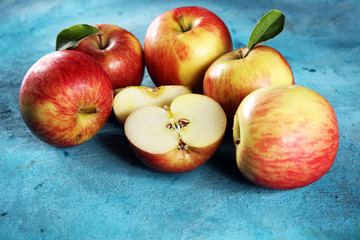 Ripe red apples with leaves on wooden background.