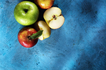 Ripe red apples with leaves on wooden background.