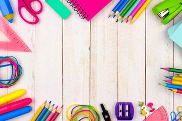 School supplies frame on a white wood background with copy space