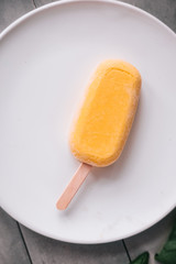Raw mango popsicle and green basil leaves from above. Grey concrete background. Minimalism food photography. Copyspace