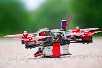 Racing drone stands on ground ready to fly. Close up view. Blurred background
