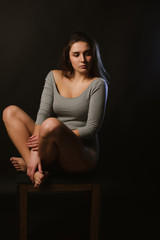 Fashionable brunette girl posing in studio during model tests dressed in grey underwear