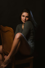 Adorable brunette woman sitting in studio during model tests, dressed in grey underwear and jeans shorts