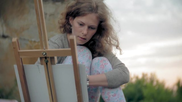Young woman draws on the easel paints and brush old vintage bridge