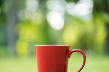 red coffee cup on green grass field in  morning time