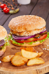 Tasty fresh meat burgers with salad and cheese served on wooden board.