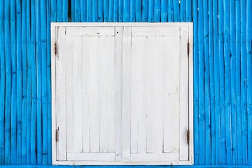 White wooden window with rusty door hinges on blue bamboo wall of a shack at the beach in the island of Koh Phangan, Thailand. Opening hours, closed concept