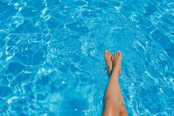 Beautiful sexy female legs against a turquoise pool background