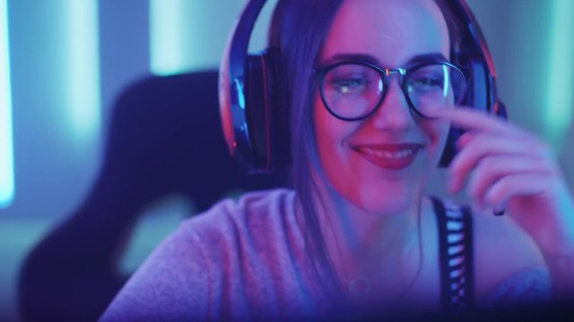 Beautiful Friendly Pro Gamer Girl Does Video Game Gameplaystream, Wearing Headset Talks / Chats with Her Fans and Team into Headphones Microphone.