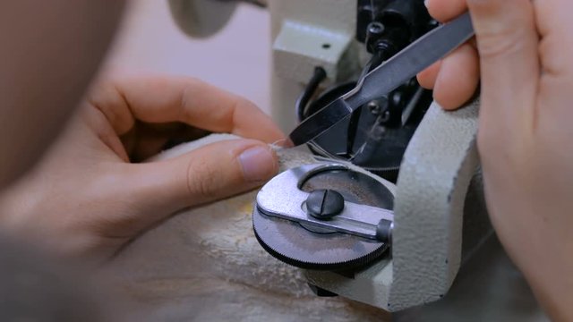 Professional male skinner, furrier using special sewing machine for stitching fur skin at atelier, workshop. Fashion and leatherwork concept