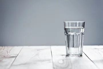 Sierkussen Glas zuiver water op neutrale achtergrond met kopieerruimte © Ivan Kruk