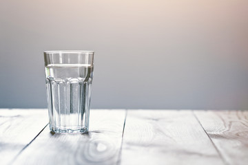 Glas zuiver water op neutrale achtergrond met kopieerruimte