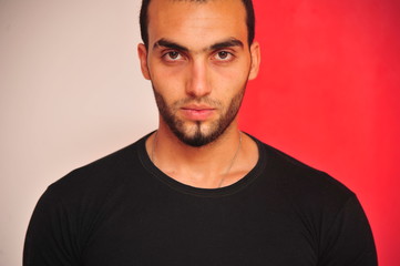 Obraz premium Arabische Junger mann schaut ernst mit roten und weißen hintergrund