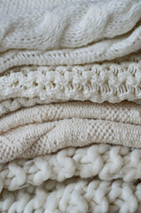 Background with warm sweaters. Pile of knitted clothes in warm shades, space for text, Autumn winter concept. Copy Space.
