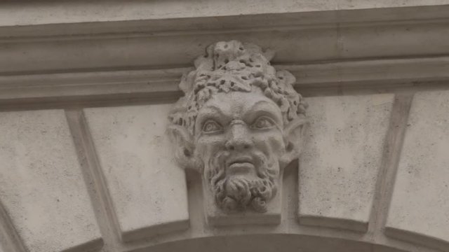 Rotating shot of faun face carved in parisian building