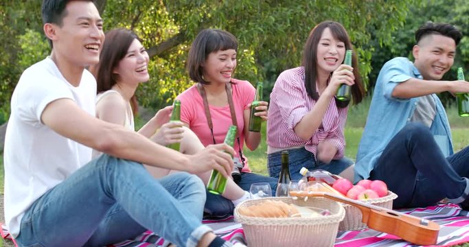 Friends go picnic together in the park and enjoy the food and drink