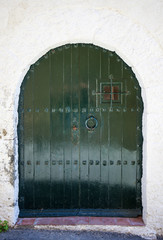 The old closed wooden door in white stone wall