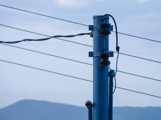Gray electric pole tension and a distant mountain in the background