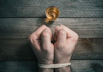 Quit Drinking Alcohol Concept With A Booze Glass In Front Of 2 Tied Stressed Looking Clenched Fists