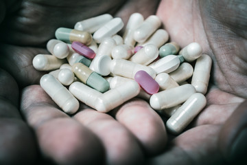 Macro Of 2 Hands Holding Several Pills In A Dark Atmosphere - Taking Too Many Pills Concept