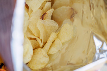 Potato chips in open snack bag close up