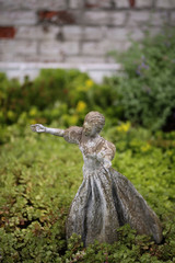 Cement Statue of a Woman with Her Arms Outstretched in a Garden