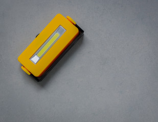 Yellow LED flashlight on floor, Minimalist style and copy space for use background, Dark color tone.
