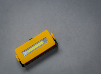 Yellow LED flashlight on floor, Minimalist style and copy space for use background, Dark color tone.