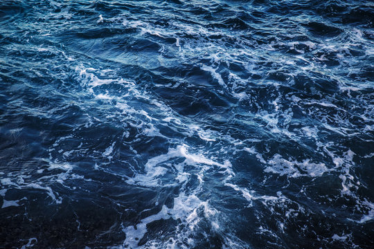 Dark blue sea water with white foam top view, natural background image