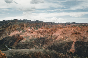 Charyn Grand Canyon with clouds and sun red orange stone Martian landscape