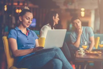 Young female student is using laptop computer in cafe