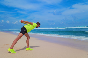 Sportsman stretching on the empty ocean beach.