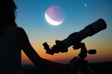 Fototapeta premium Girl looking at lunar eclipse through a telescope. My astronomy work.